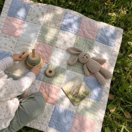 Pastel patchwork baby quilt as a play mat on the grass - free baby quilt patterns